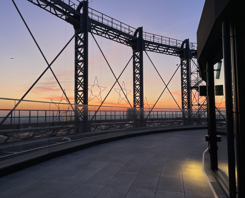 Die Dachterrasse des Gasometers auf 66 Metern Höhe in schöner Abendstimmung mit Sonnenuntergang im Hintergrund.
