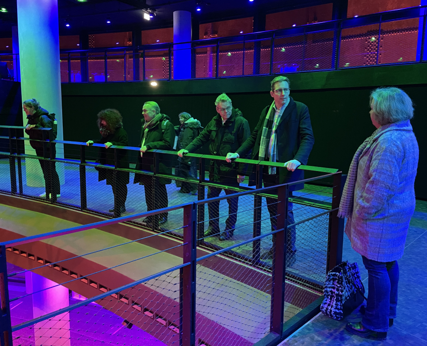 Der Besuch aus Amstelveen steht zusammen mit den Gästen aus dem Bezirk auf einer Empore im Gasometer. Von dort haben sie einen guten Blick auf die untere Bühne im größten Veranstaltungssaal des Gasometers, der für sie in bunten Farben angestrahlt wird.