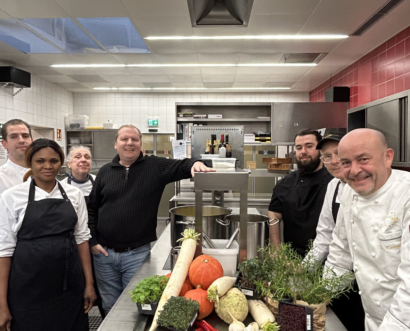Thomas Kammeier, gastronomischer Leiter des EUREF-Campus, zusammen mit seinem Gastro-Team und Gernot Zessin in einer der Küchen auf dem EUREF-Campus, vor einem Berg Gemüse, der für die Suppe verwendet wird.