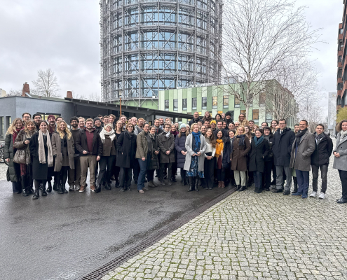 Gruppenbild auf dem EUREF-Campus in Berlin mit dem Gasometer im Hintergrund.