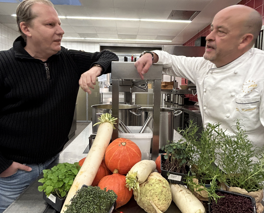 Gernot Zessin von KUBUS und Thomas Kammeier, der Gastronomische Leiter auf dem EUREF-Campus, zusammen in der Küche vor einem Gemüse-Berg, bereit zum Kochen der Suppe.