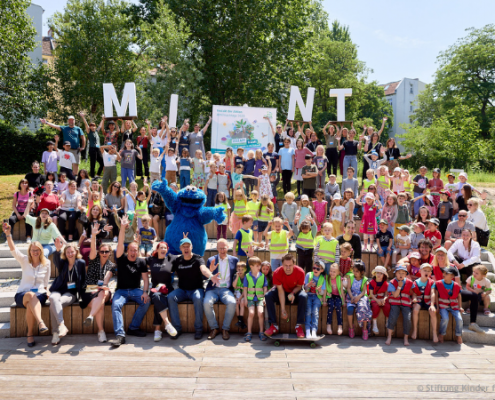 Gruppenbild der 100 begeisterten Kita- und Grundschulkinder zusammen mit Bildungsministerin Prien, Moderator André Gatzke und dem Krümelmonster während der MINTmachtage auf dem EUREF-Campus
